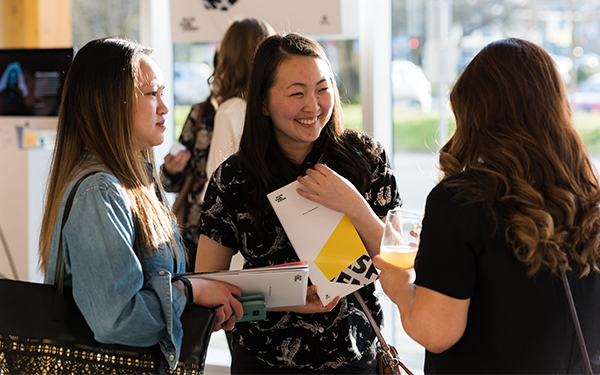 3 guests smiling and chatting at Grad Show